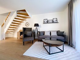 Wohnraum mit Sofa, Sessel, Glastisch und Blick auf die Treppe im Ostsee-Domizil Ferienhaus Hohwacht