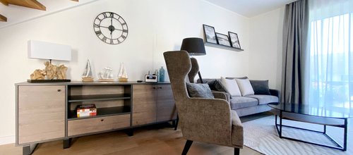 Wohnraum mit Sideboard, Sofa, Sessel und Glastisch, Blick auf Sitzbereich im Ferienhaus Ostsee-Domizil