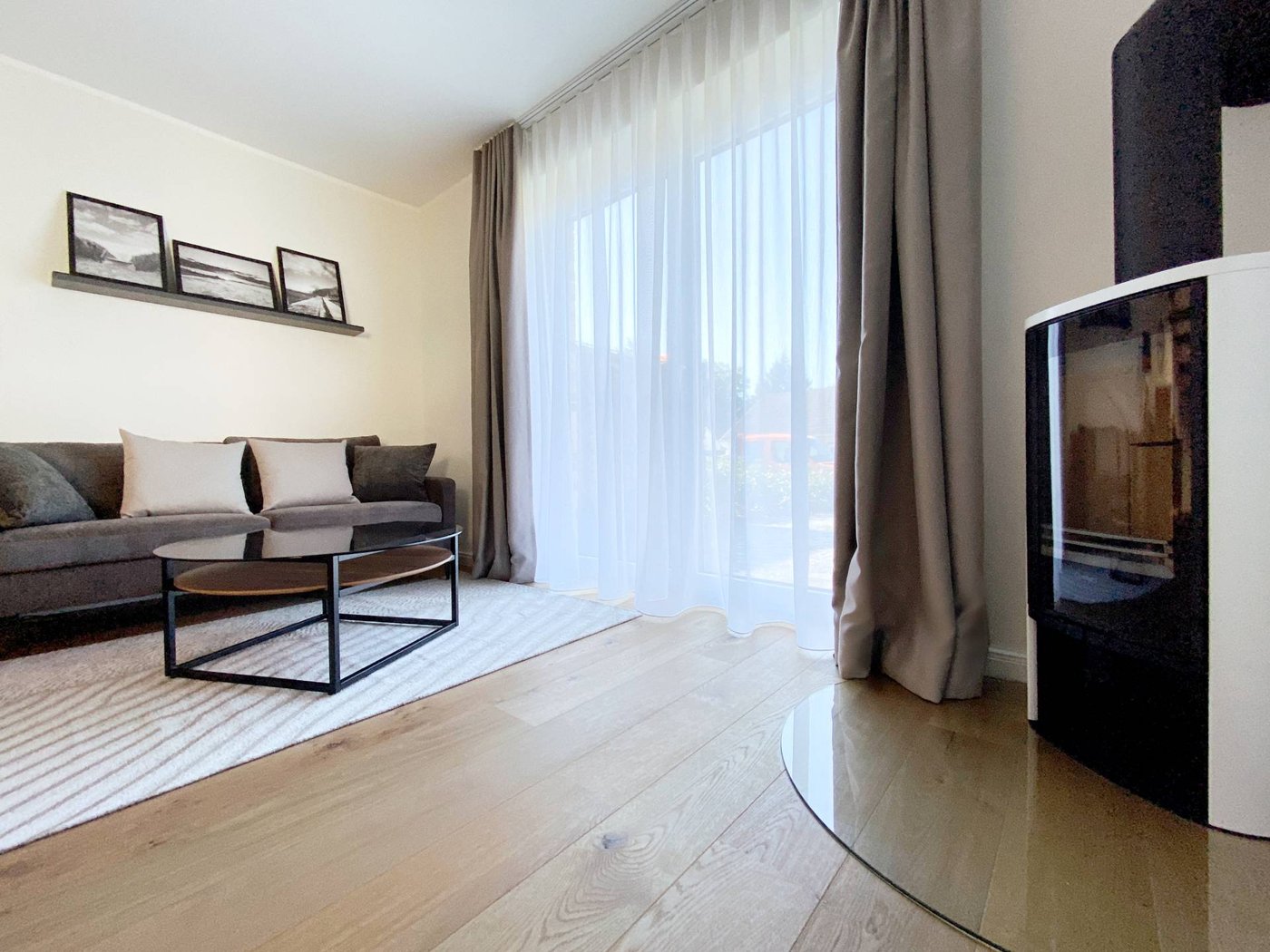Wohnraum mit grauer Couch, Glastisch und Kamin im Ferienhaus Ostsee-Domizil