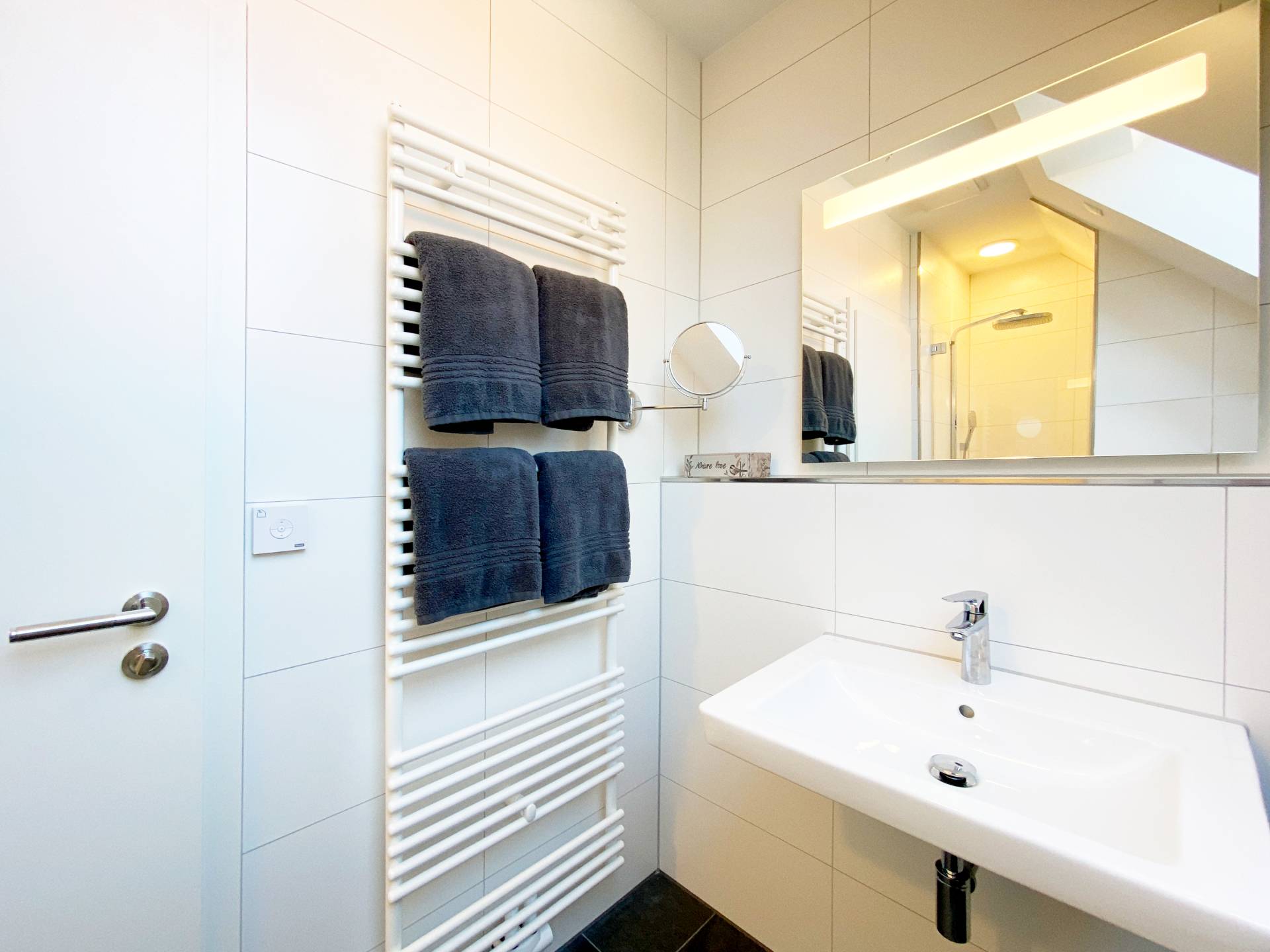 Badezimmer mit Handtuchheizung, Waschtisch & Spiegel im Ostsee-Domizil Ferienhaus Hohwacht