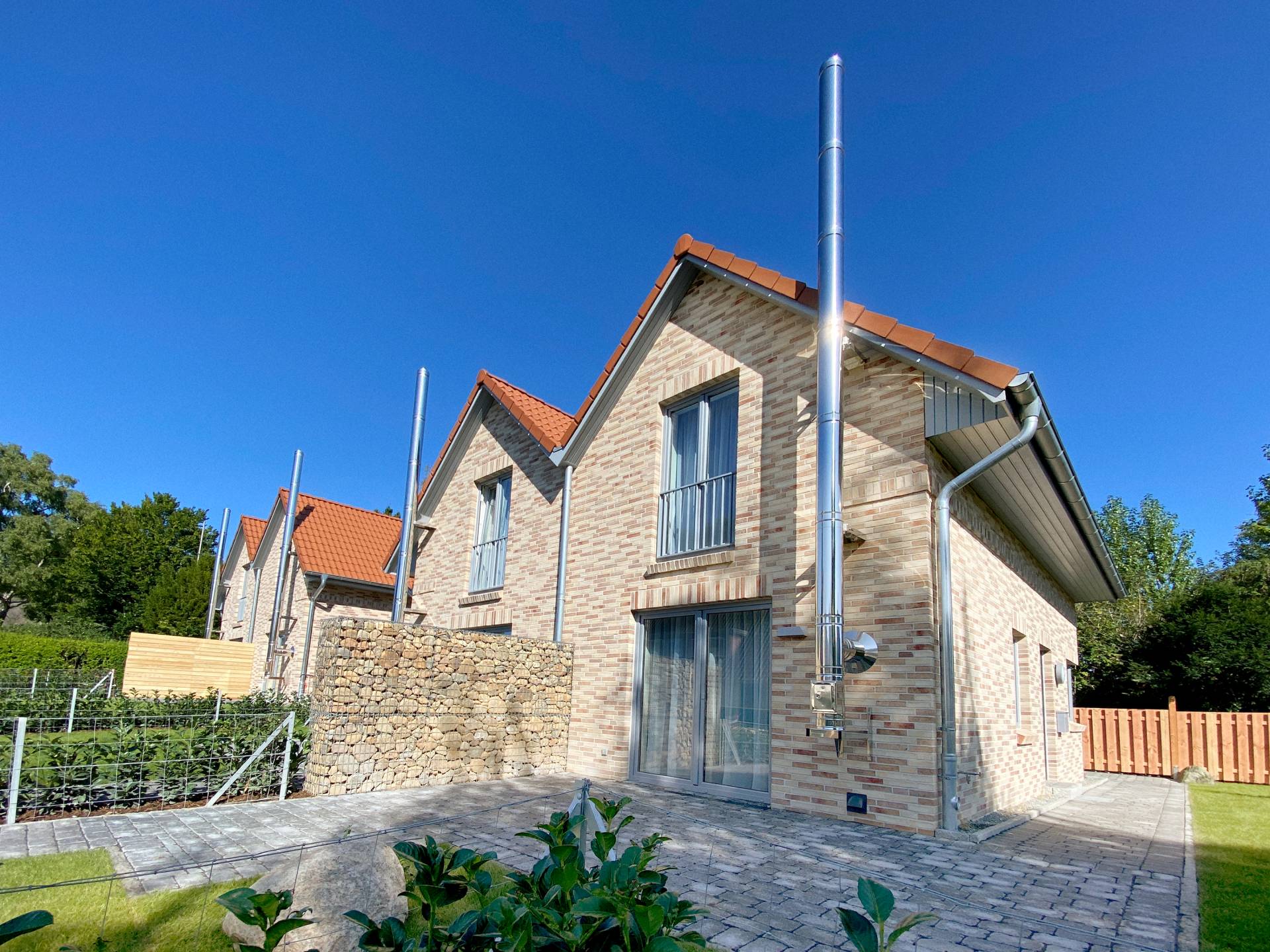 Außenansicht Doppelhaushälfte mit Garten vor blauem Himmel | Ferienhaus Ostsee-Domizil Außenansicht und Garten der Doppelhaushälfte vom Ostsee-Domizil Ferienhaus Hohwacht