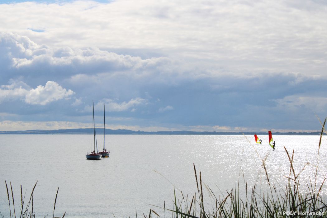 Zwei Boote und Windsurfer liegen in der Hohwachter Bucht der Ostsee